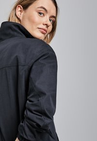 Donkerblauwe overhemdd met hoge kraag, opgerolde mouwen en een gladde, gestructureerde stof. Heeft een strak design en een comfortabele pasvorm.