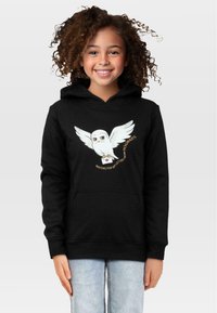 Czarna bluza z kapturem z rysunkiem sowy z rozpostartymi skrzydłami oraz napisem "Czekam na mój list z Hogwartu" w kolorze żółtym. Miękka tkanina, luźny krój.