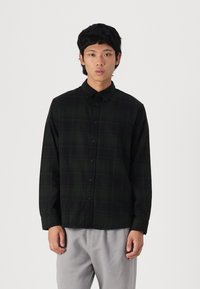 Long-sleeve, button-up shirt in dark green plaid fabric. Features a collar, front buttons, and a relaxed fit. Soft texture, minimal design.