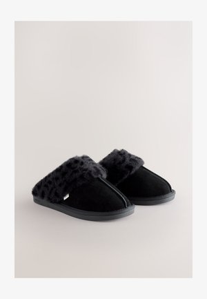 Pantofole in suede nero con una morbida tomaia in pelliccia sintetica nera con stampa leopardata e suola piatta in gomma, caratterizzate da una cucitura lungo la parte anteriore.