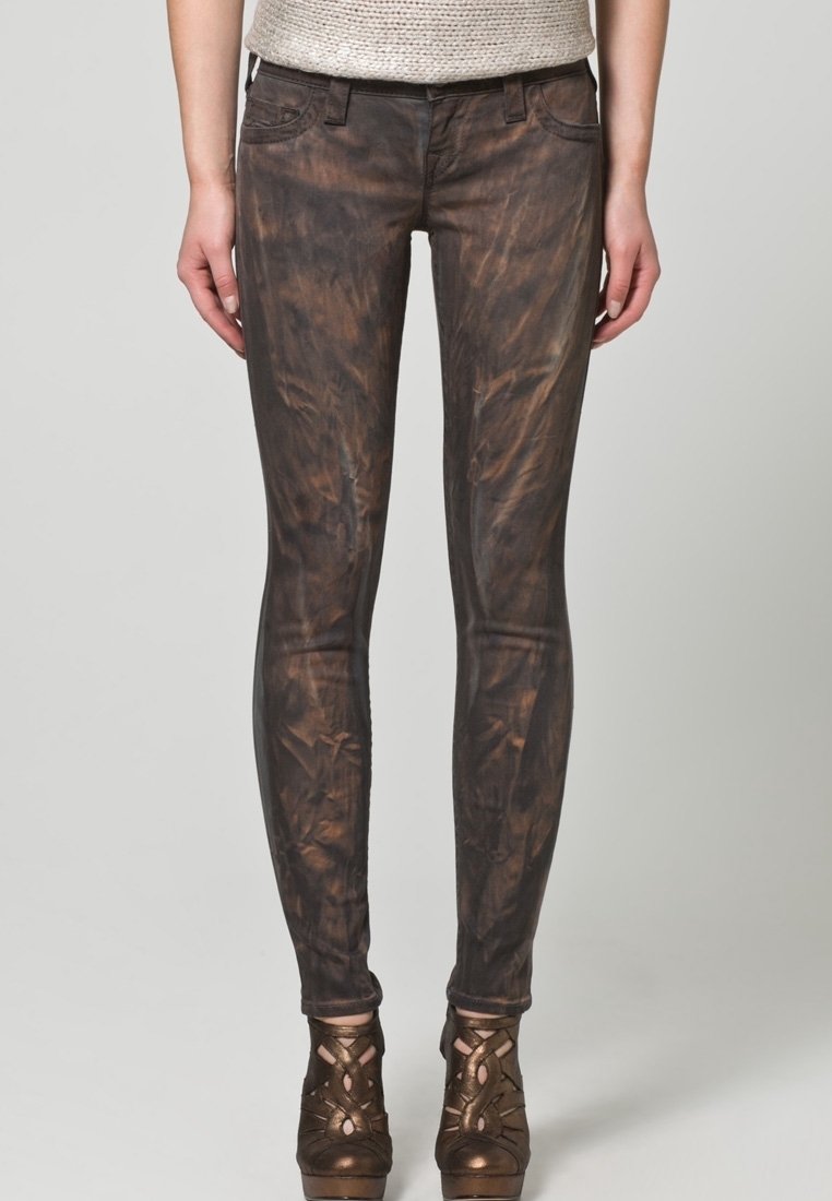 Mörkbruna skinny jeans med en ruggad textur, framfickor och kontrasterande sömmar, tillsammans med bronsfärgade högklackade skor.