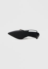 Μαύρο γυναικείο παπούτσι με αιχμηρή μυτερή μύτη και λουράκι στον αστράγαλο, κατασκευασμένο από λείο δέρμα, με λεπτό τακούνι και διακοσμητικό χρυσό στοιχείο κοντά στο άνοιγμα.