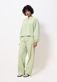Groen en wit geruite loungewear set met een loszittend top met een korte knoopsluiting en lange mouwen, gecombineerd met wijde pantalons.