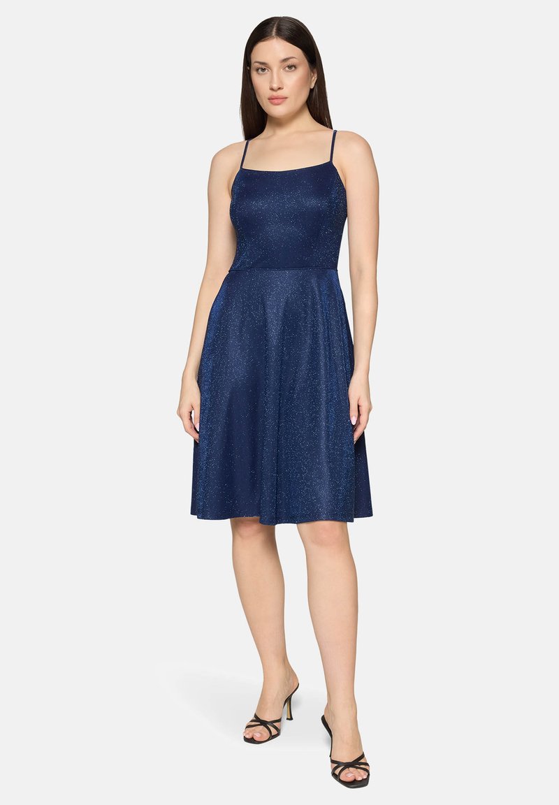 Robe bleu marine sans manches avec un corsage ajusté et une jupe évasée, confectionnée dans un tissu scintillant. Elle présente des bretelles fines et un ourlet arrivant au genou.