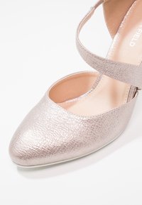 Chaussure plate texturée rose clair scintillante avec bout arrondi et bride à la cheville sur fond blanc.