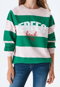 Sudadera a rayas verdes y rosas con el llamativo texto blanco "PERFECT" y un acento rojo de "beach song", con mangas acampanadas y textura suave.