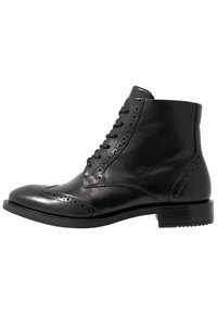 Botín de cuero negro hasta el tobillo con puntera redondeada, cordones en la parte delantera, detalle de perforaciones decorativas y un tacón bajo apilado.