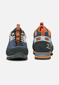 Scarpe da trekking grigie e blu navy, con accenti arancioni, una tomaia texturizzata, suole in gomma nera e un collare imbottito per il supporto.