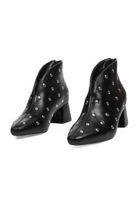 Botas de cuero negras hasta el tobillo con punteras puntiagudas, decoradas con tachuelas plateadas, que cuentan con una cremallera lateral y tacones cuadrados gruesos.