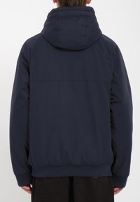 Marineblauwe hoodie met een ontspannen pasvorm, geribde manchetten en zoom, met een gladde buitenkant en een minimalistisch ontwerp.