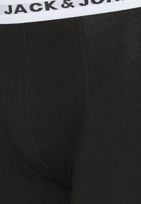 Schwarze Boxer-Briefs mit einem weißen elastischen Bund. Der Bund trägt den Schriftzug "JACK & JONES." Hergestellt aus einem weichen, dehnbaren Material.