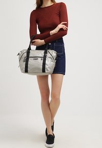 Borsa a tracolla in nylon argentato con manici neri, caratterizzata da una forma rettangolare, texture liscia e chiusura a doppia cerniera.