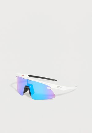 Lunettes de soleil de sport blanches avec verres bleus miroirs et plaquettes de nez noires, inclinées sur un fond gris neutre.