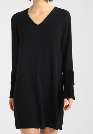 Vestido negro de corte recto con escote en V y mangas largas. Las mangas presentan detalles plisados. Fabricado en un tejido ligero.