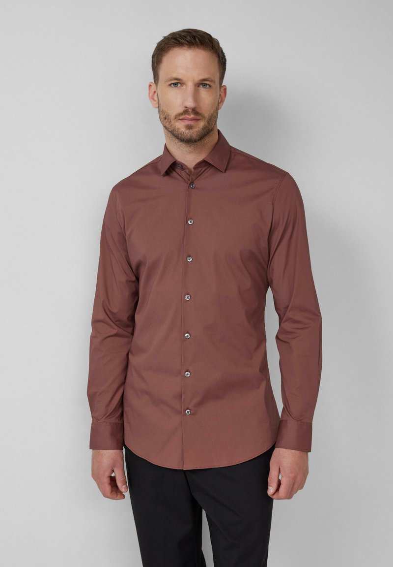 Roestrode blouse met lange mouwen en knoopsluiting, met een getailleerde pasvorm, voorzien van een gespreide kraag en glanzende knoopaccenten tegen een effen achtergrond.