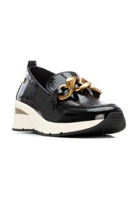 Zapato de charol negro con suela de cuña, que presenta un destacado acento de cadena dorada y una textura de superficie lisa.