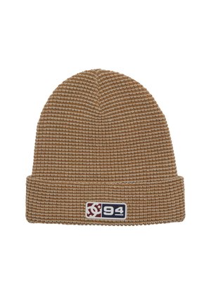 Bonnet en tricot marron avec un motif texturé, présentant un revers replié et un patch logo coloré sur le côté.