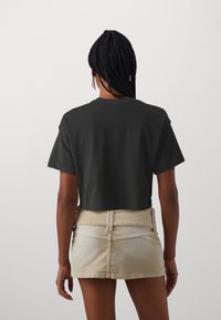 Svart kortärmad t-shirt med rund halsringning, parat med en beige manchestervelour mini kjol och detaljer i texturerat tyg.