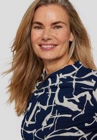 Navyblaues Oberteil mit einem abstrakten weißen Muster. Die Stoffstruktur ist weich, und die Passform wirkt lässig. Runder Ausschnitt und kurze Ärmel.