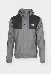 Graue Jacke mit schwarzer Einfassung, aus leichtem Material. Verfügt über eine Kapuze, Druckknöpfe, Fronttaschen und ein Logo auf der linken Brust.