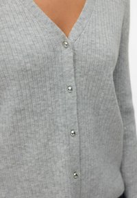 Grijze geribde cardigan met een V-hals en zilveren knoopsluitingen. Zachte textuur met verticale lijnen en aansluitende mouwen. Lichtgewicht stof.