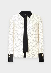 Long-sleeve blouse in ivory with black geometric print, contrasting black collar and cuffs, and a black tie detail. Gold button accents at cuffs.