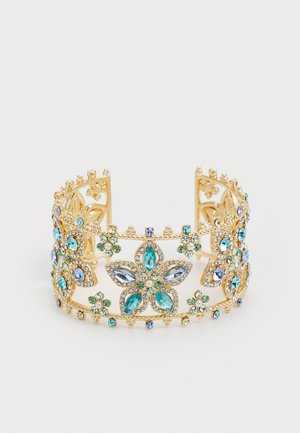Zelta tonis aproce ar florālo dizainu, dekorēta ar tirkīza, ziliem un zaļiem rhinestones, akcentēta ar sīkām caurspīdīgām pērlēm. Atvērtā dizaina.