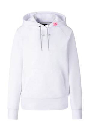 Kobieta nosząca oversize białą bluzę z kapturem, neonowo różową spódnicę na czarnych legginsach, masywne czarne buty i duże refleksyjne okulary przeciwsłoneczne stojąca na białym tle.