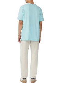 Lichtblauw katoenen T-shirt met een ontspannen pasvorm, korte mouwen en een ronde hals, gecombineerd met off-white recht-pasende broeken en casual schoenen.