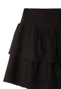 Gonna nera a strati realizzata in tessuto testurizzato con motivi di occhiello. Presenta una vita smock e due strati fluttuanti.