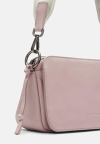Pink leather crossbody bag with a smooth texture, featuring a zip closure and a detachable beige fabric strap with a clip attachment.