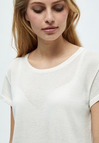 Biela, krátkopyjá t-shirt s okrúhlym výstrihom, vyrobená z textúrovaného, ľahkého materiálu. Mierna priesvitnosť a voľný strih.