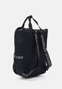 Czarna torba tote wykonana z nylonu, o prostokątnym kształcie, z dwoma uchwytami i z wyraźnym logo w białym kolorze z boku i na pasku.