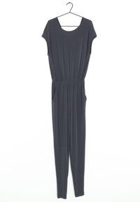 Mono de jersey gris con mangas cortas, escote en forma de barco, cintura elástica, bolsillos laterales y piernas ajustadas. Cuelga de una percha negra.