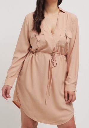 Vestido largo de manga larga en rosa empolvado, con escote en V, dos bolsillos en el pecho, cintura ceñida y dobladillo curvado. Presenta una tela suave y ligera.