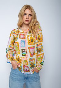 Bunt gemusterte Bluse mit einem kragenlosen Ausschnitt, durchgehender Knopfleiste und leichtem, durchsichtigen Stoff mit floralen und geometrischen Mustern.