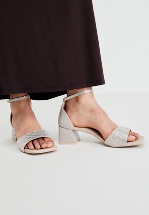 Open sandalen met hak in lichtroze, voorzien van een gestructureerde, glinsterende band en een enkelbandje, met een brede blokhak.