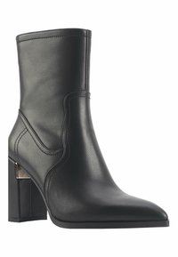 Black leather ankle boot with a pointed toe, a block heel, and curved stitching details, featuring metallic accents at the heel.