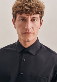Zwarte overhemd met een gestructureerde kraag, knoopsluiting aan de voorkant en een borstzak; gladde textuur en een getailleerd ontwerp.
