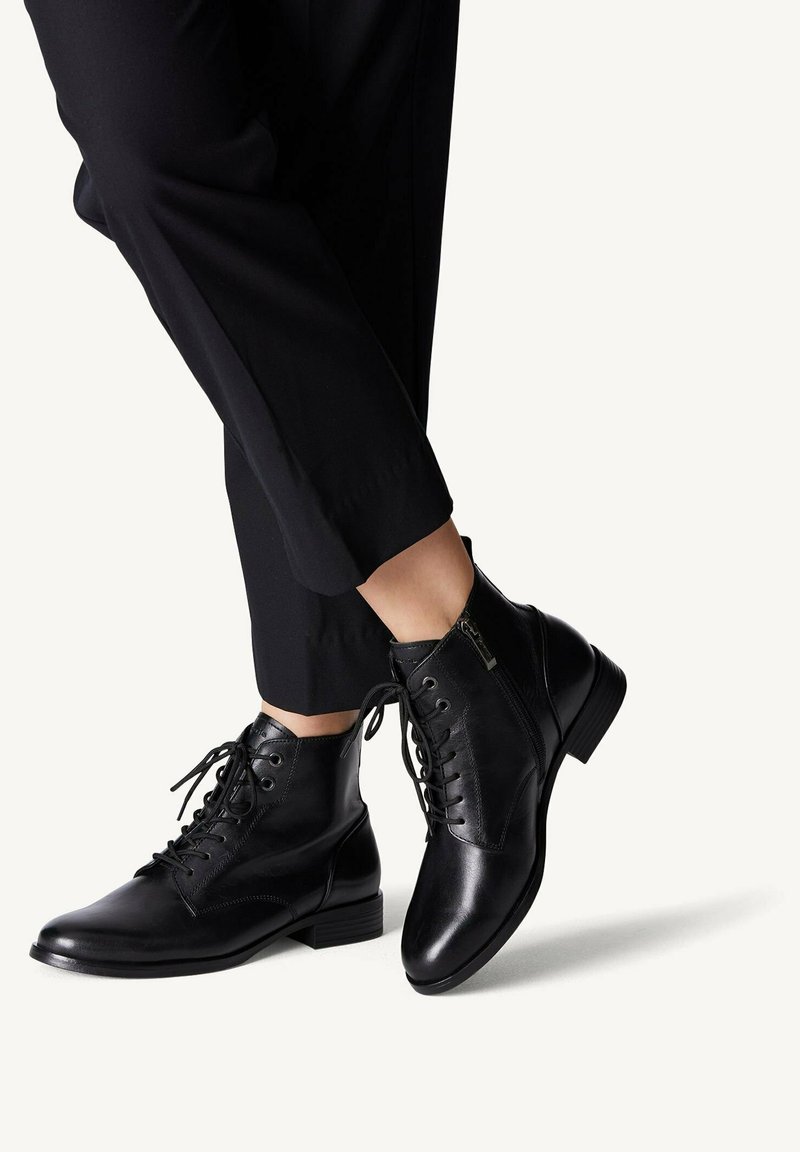 Bottines en cuir noir avec un bout rond, un laçage à l'avant et une fermeture éclair sur le côté. Caractérisées par une texture lisse et un petit talon carré.
