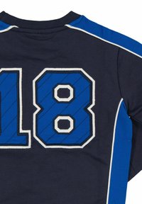 Musta pitkähihainen paita, jossa on suuri sininen ja valkoinen numeroitu grafiikka "18" selässä, ja olkapäillä kontrastiväri siniset korostukset.