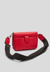 Rød tekstureret lædertaske med klaplukning, aftagelig sort rem og branddetalje. Kompakt design, der er velegnet til at bære essentielle ting.