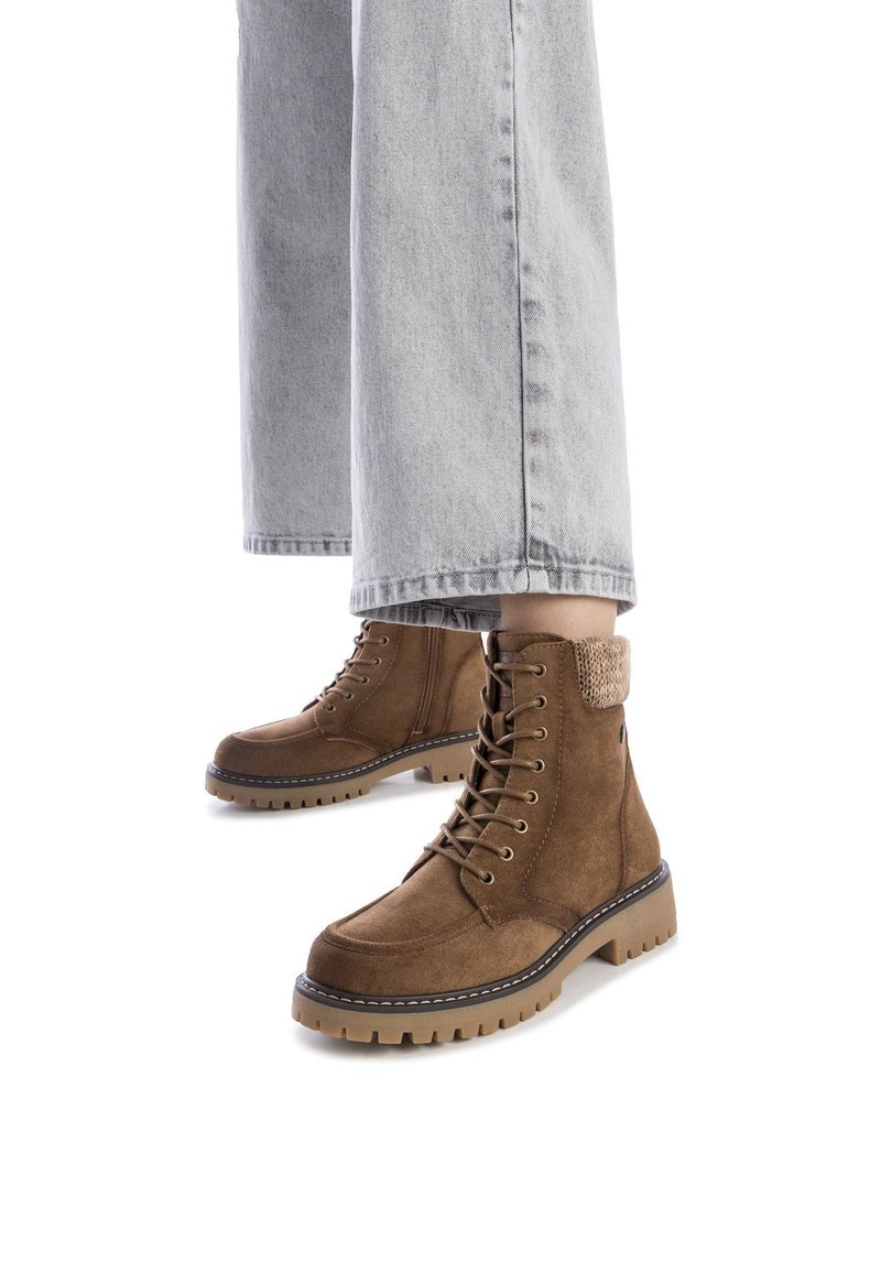 Las botas de tobillo de ante marrón cuentan con un diseño de cordones, un cuello acolchado y una suela de goma rugosa y texturizada con costuras en contraste.