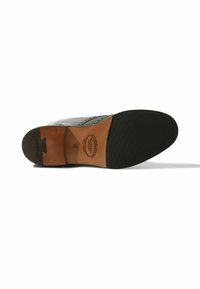 Suola di scarpa da uomo con accentuazione in pelle marrone sul tallone, fondo in gomma nera e dettaglio di cucitura decorativa lungo il bordo. Design leggero e flessibile.