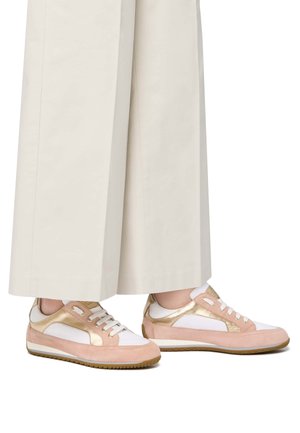 Baskets en daim rose avec des accents dorés, présentant des panneaux blancs et des lacets blancs, associées à un pantalon large crème. Semelles en caoutchouc marron.