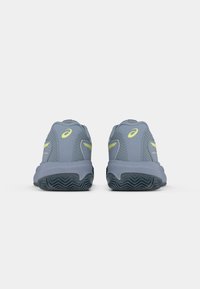 Sive atletske čevlje z mrežasto zgornjico, rumenimi akcenti in teksturirano gumijasto podplatom, videni s hrbtne strani.