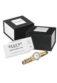 Montre-bracelet en métal doré avec un cadran blanc, des index noirs et un bracelet à maillons, accompagnée d'un emballage noir et blanc et d'une carte de garantie.