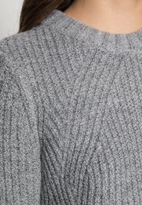 Maglione grigio lavorato a maglia con un motivo testurizzato e scollo rotondo. Il design ha un aspetto morbido e peloso con finitura a costine.