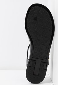 Svart sandal sula med strukturerad yta som har ett "RL" mönster, böjd form med en slät finish och en cirkulär detalj nära hälen.