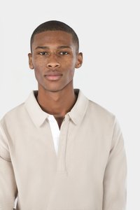 Beige Baumwoll-Polohemd mit weißem Kragen und Knopfleiste, langen Ärmeln und einer lockeren Passform.